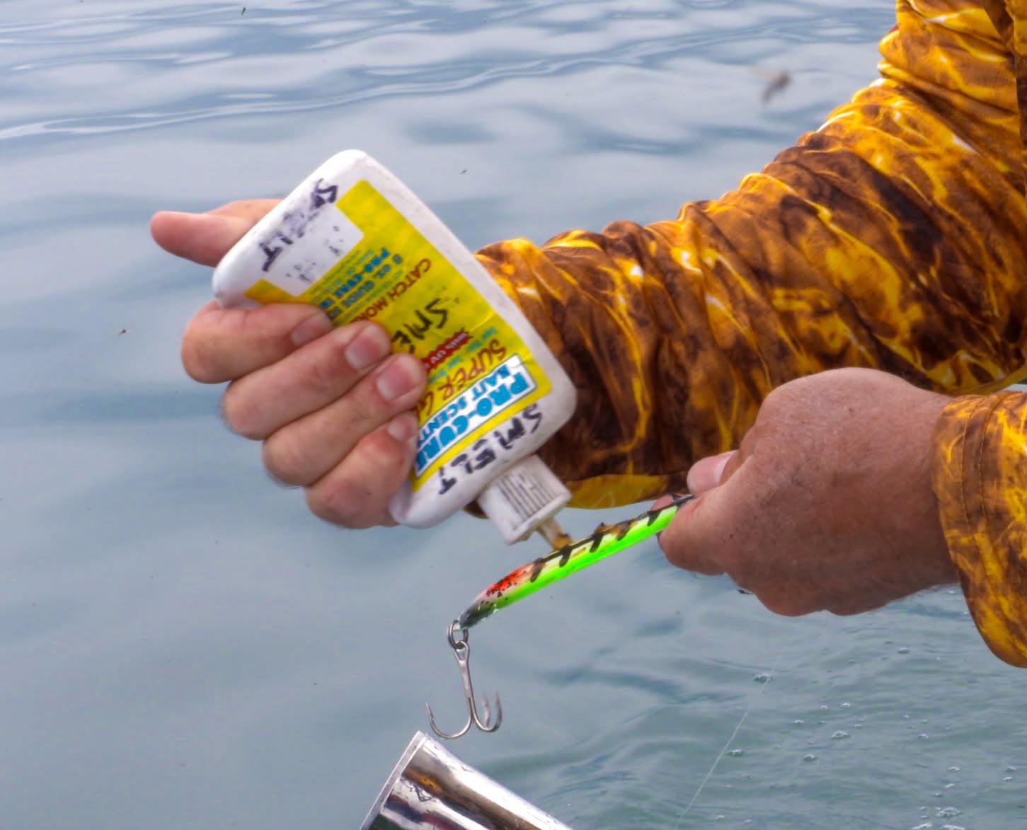 Hands applying Pro-Cure Smelt Super Gel to a chartreuse crankbait